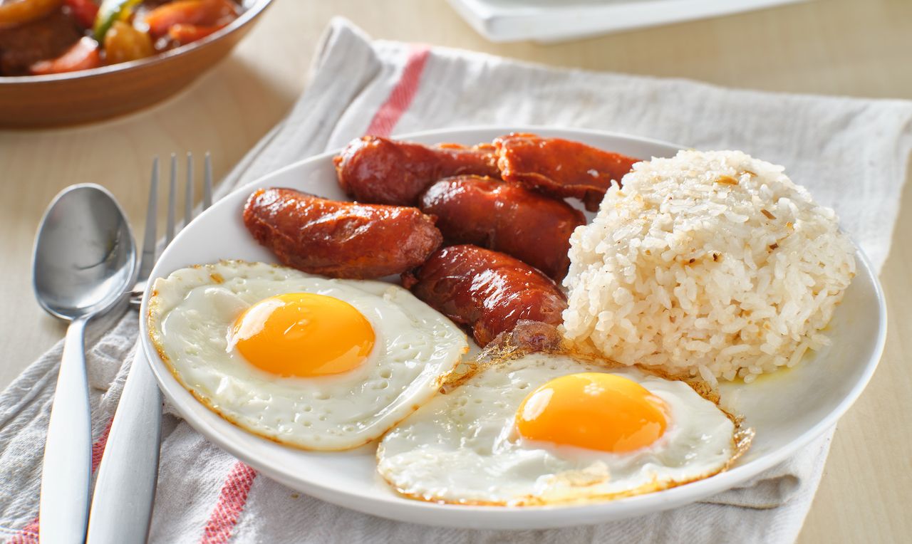 filipino silog breakfast with garlic fried rice, longsilog, and two sunny side up eggs