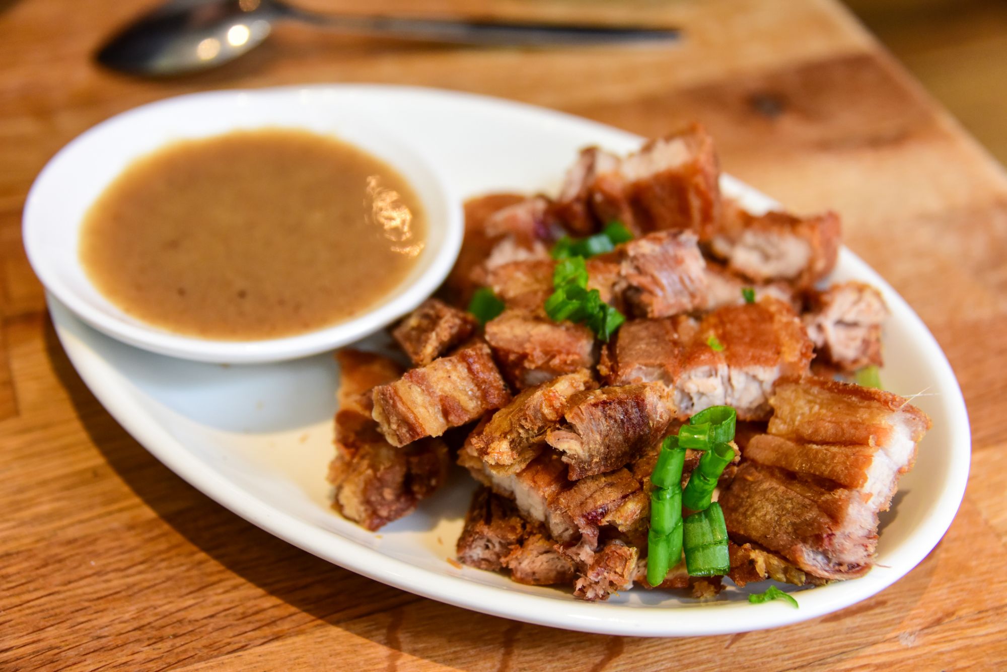 Close up of a plate of Filipino deep fried pork belly served with sweet sauce